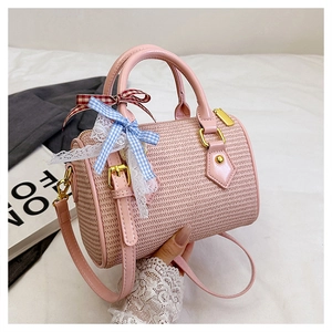 Détail du sac Boston rose tissé avec nœuds décoratifs et finitions métalliques dorées