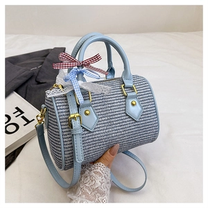Détail d'un sac Boston tissé bleu avec nœuds décoratifs et bandoulière réglable