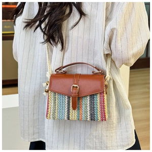 Detail view of colorful striped straw bag with brown leather flap and rope strap