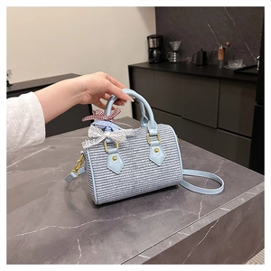 Détail d'un sac Boston tissé bleu clair avec nœuds porté à la main