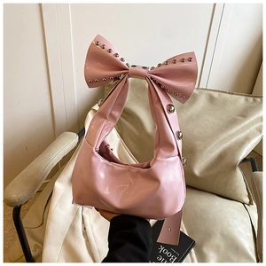 Detail of pink bow handbag with shiny patent leather and silver metal rivet accents