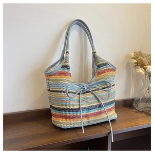 Close-up of colorful striped straw tote with blue leather bow and woven handle detail