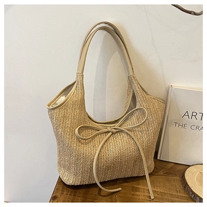 Detail of hand-woven straw tote with leather handles and decorative bow knot detail