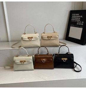 Multiple colors of crocodile embossed trapezoid bags with gold round buckles on steps