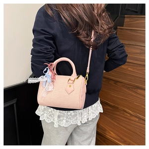 Détail du sac tonneau rose tissé avec rubans en dentelle et bandoulière réglable