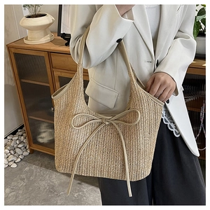 Detail of woven straw tote bag featuring a decorative bow and fine V-shaped textures