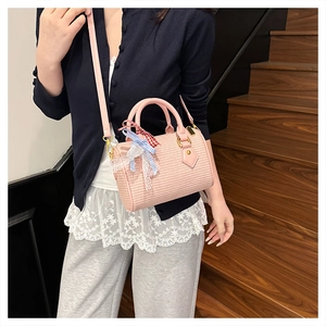 Détail d'un sac barillet tressé rose avec nœuds à carreaux et ruban dentelle porté