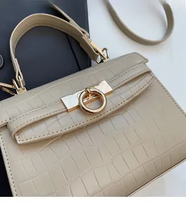 Detail of light beige stone-textured leather bag with golden round hardware lock and handle