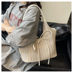 Détail du sac cabas tissé beige avec texture en V et pompon en cuir blanc