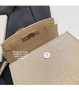 Detail of beige crocodile embossed bag showing the secure magnetic snap closure design