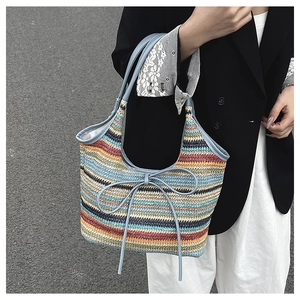 Detailed texture of multi-color woven straw bag with blue bow and handle accents