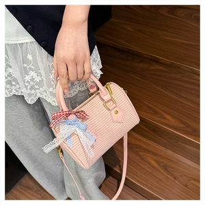 Détail du mini sac Boston en tricot rose avec nœud en dentelle et finitions dorées