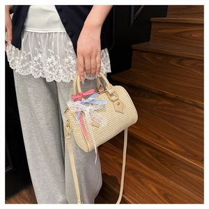 Détail du sac tonneau en paille tressée avec nœuds décoratifs et lanières en cuir