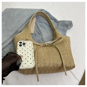 Top view of beige straw woven tote bag featuring leather knot detail and curved handles