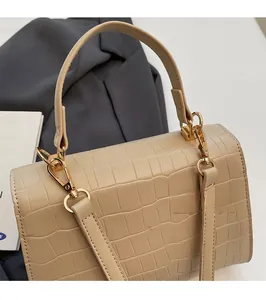 Detailed close-up of beige crocodile pattern leather and polished golden buckle on bag