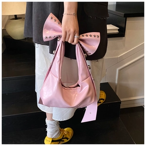 Detail of pink patent leather handbag with bow shape and silver metal rivet studs