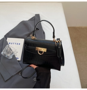 Detail of black crocodile texture handbag with golden ring lock and elegant top handle