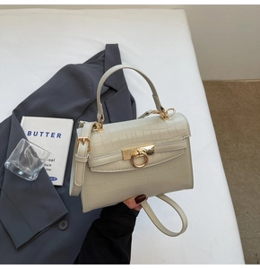 Detail view of crocodile-patterned cream tote bag with elegant golden ring lock