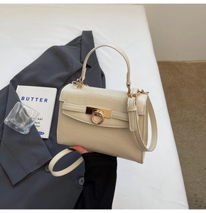 Close-up of cream white crocodile embossed leather bag with golden ring buckle