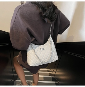 Chic white quilted hobo bag with silver chain strap shown in a stylish street setting