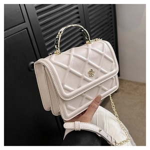 Dettaglio borsa trapuntata beige con chiusura a camelia dorata e manico in metallo