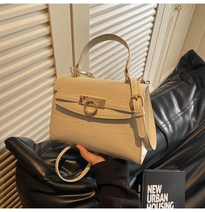 Detail of off-white crocodile pattern handbag with gold ring clasp and top handle