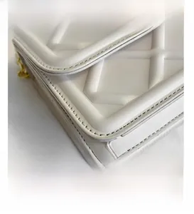 Dettaglio della trama a rombi bianchi e cuciture fini su una borsa con catena