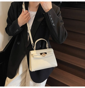 Mini white croc-embossed handbag with gold ring clasp shown on model for outfit styling
