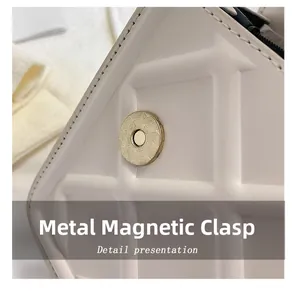 Macro della fibbia magnetica dorata e pelle bianca goffrata sulla borsa a mano