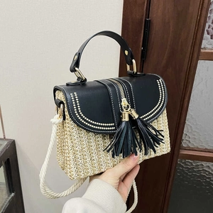 Handmade woven straw bag with black leather flap and tassels for a stylish 2025 trendy look