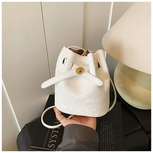 Detail view of white snakeskin texture bucket bag with elegant golden twist-lock closure