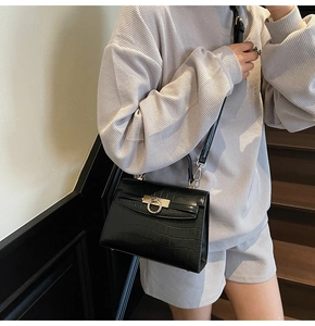 Detail of black faux crocodile leather bag with gold buckle on a chic shoulder strap
