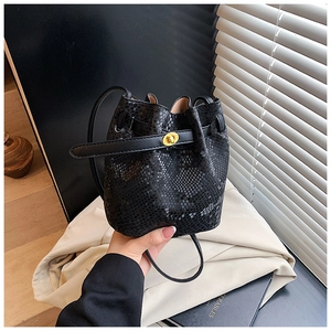 Detail of black snake-patterned bucket bag featuring a secure gold twist-lock closure