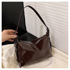 Detail of dark brown glossy patent leather shoulder bag with silver metal ring ornaments