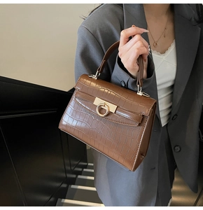 Close-up of brown crocodile texture leather bag with elegant gold circular lock detail