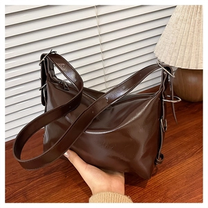 Detail of soft dark brown glossy faux leather tote bag with silver hardware and strap