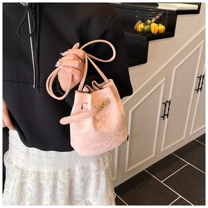 Detail of pink bucket bag with snakeskin texture and golden twist lock on shoulder strap