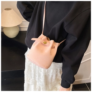 Detail view of mini pink snake-texture bucket bag with gold clasp and slim strap