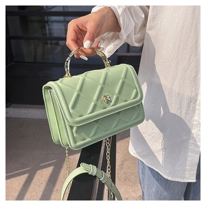 Dettaglio della borsa trapuntata verde menta con chiusura a camelia dorata e manico metallico