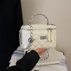 Chic quilted cream crossbody bag with silver chain strap held against a travel background