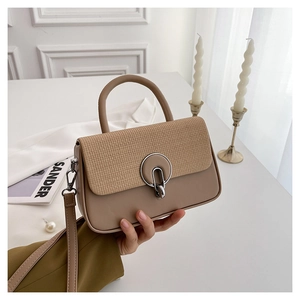 Detail of beige leather bag with woven flap and silver metal lock held in hand