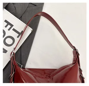 Detail of burgundy glossy leather tote bag with silver rings and wide shoulder strap