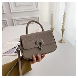 Detail of crossbody bag featuring textured woven flap and silver metal ring buckle