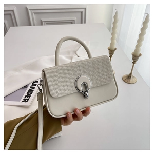 Close-up of minimalist cream white handbag featuring knit texture and silver buckle
