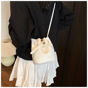 Close-up of white bucket bag with snake-effect embossing and golden metal lock