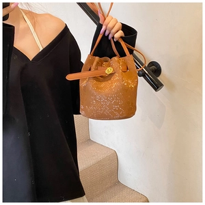 Close-up of brown snakeskin embossed bucket bag with golden rotating buckle and leather strap