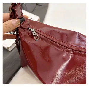 Detail of smooth silver zipper on dark red leather tote bag with polished texture