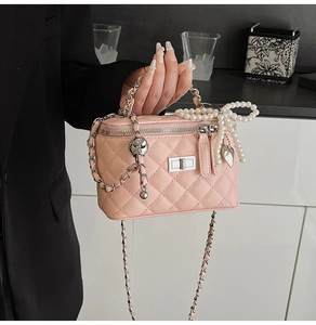 Detailed view of a pink quilted bag with silver chain strap and pearl bow charm accessory