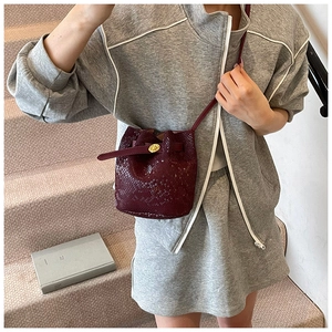 Detail of burgundy snakeskin bucket bag with gold twist lock and elegant leather strap