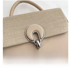 Detail of beige shoulder bag with silver ring buckle and woven textured fabric texture